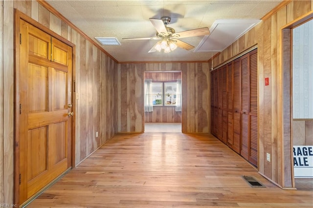 spare room with light hardwood / wood-style floors, ceiling fan, ornamental molding, and wood walls