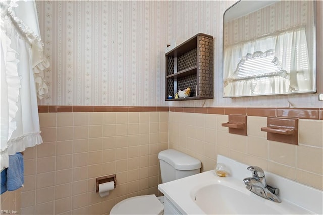 bathroom featuring vanity, toilet, and tile walls