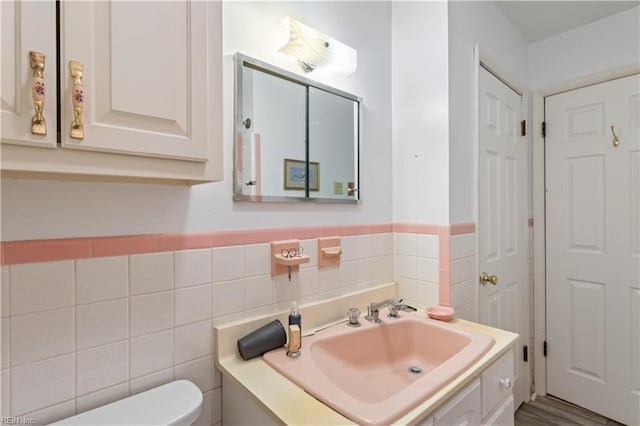 bathroom with hardwood / wood-style floors, vanity, toilet, and tile walls