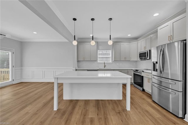 kitchen with decorative light fixtures, a kitchen island, a breakfast bar, sink, and stainless steel appliances