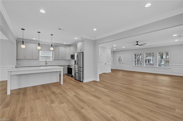 kitchen featuring appliances with stainless steel finishes, crown molding, a kitchen island, and pendant lighting