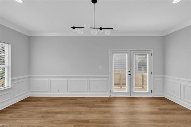 unfurnished dining area featuring crown molding, french doors, and light wood-type flooring