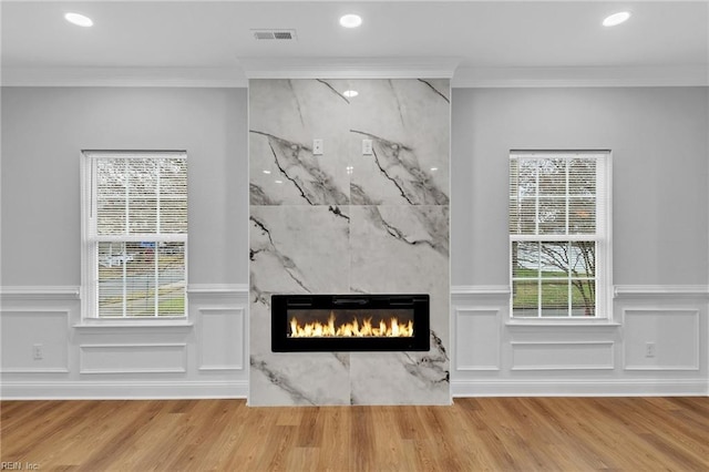 interior details with a high end fireplace, ornamental molding, and hardwood / wood-style flooring