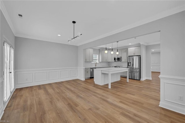 kitchen featuring pendant lighting, a kitchen island, crown molding, appliances with stainless steel finishes, and white cabinets