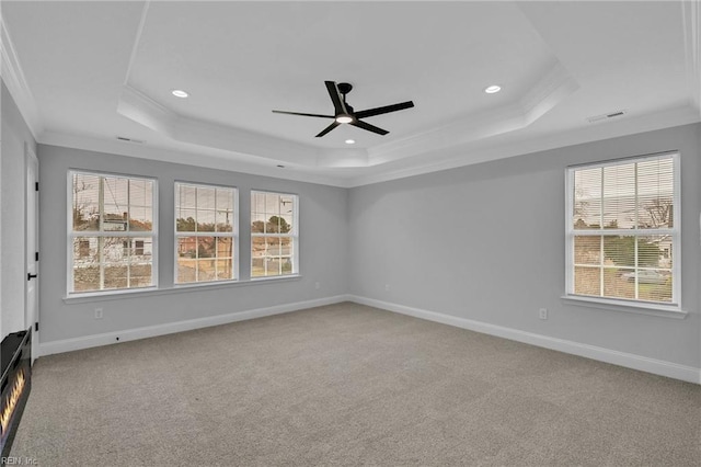 carpeted empty room featuring a raised ceiling, ceiling fan, and ornamental molding