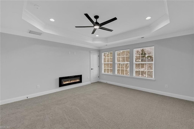 unfurnished living room featuring ceiling fan, carpet, crown molding, and a raised ceiling