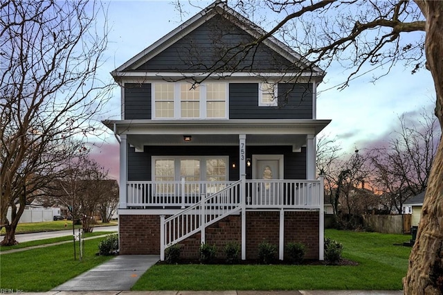 view of front facade featuring covered porch and a lawn