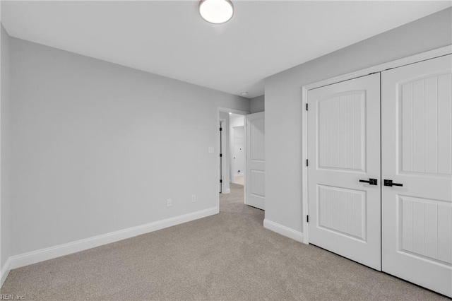 unfurnished bedroom with light carpet and a closet