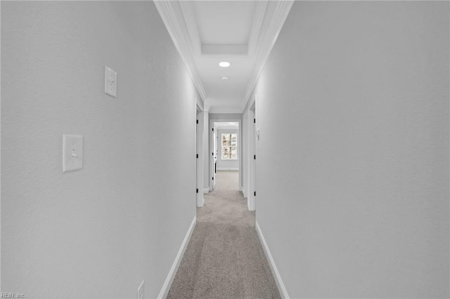 hallway featuring light colored carpet and a tray ceiling