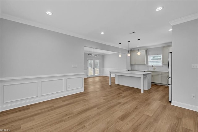 kitchen with ornamental molding, a kitchen island, pendant lighting, a breakfast bar, and sink