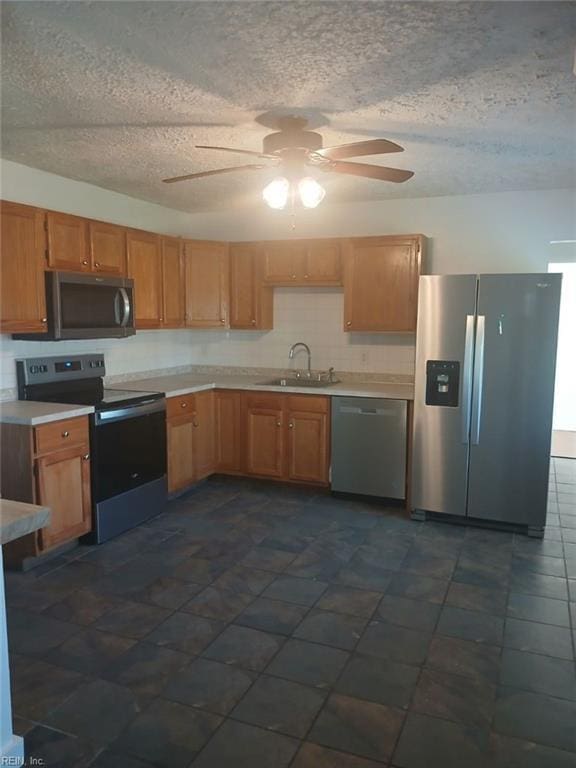 kitchen featuring dark tile patterned flooring, sink, ceiling fan, a textured ceiling, and appliances with stainless steel finishes