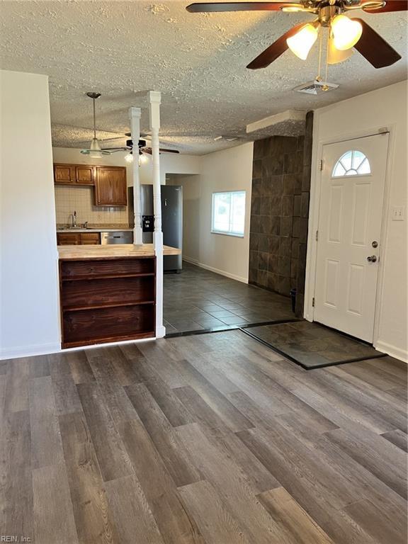 kitchen with stainless steel refrigerator with ice dispenser, hanging light fixtures, a textured ceiling, dark hardwood / wood-style flooring, and backsplash