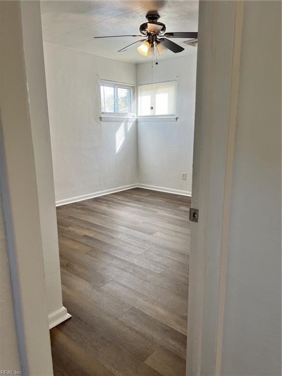 empty room with dark wood-type flooring and ceiling fan