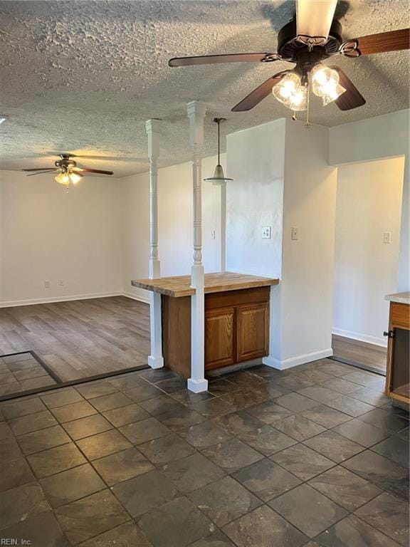 kitchen with ceiling fan, decorative light fixtures, and a textured ceiling