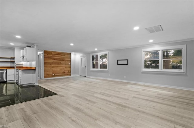 unfurnished living room featuring light hardwood / wood-style floors, a wealth of natural light, and ornamental molding