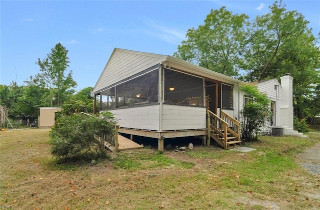 back of property featuring a sunroom, central AC unit, and a yard