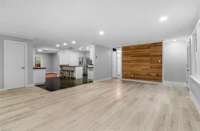 unfurnished living room featuring light hardwood / wood-style flooring and crown molding