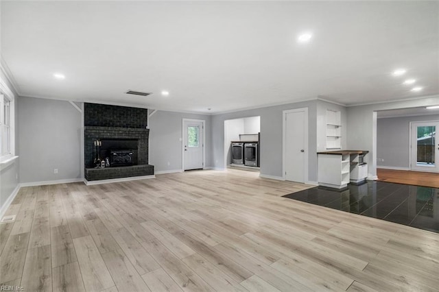 unfurnished living room with light hardwood / wood-style flooring, a healthy amount of sunlight, and a brick fireplace