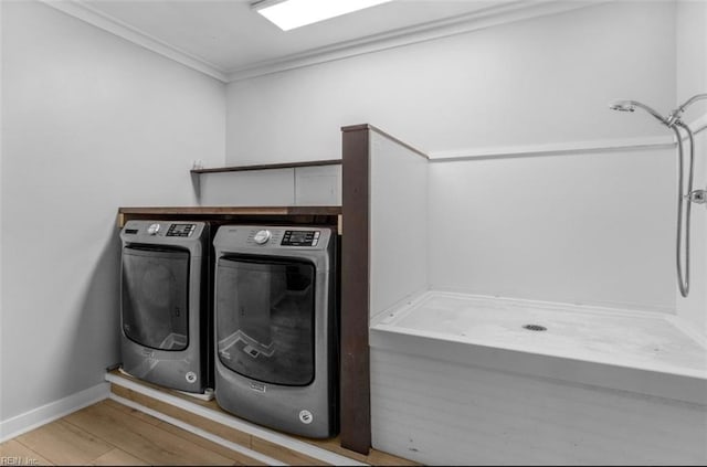 laundry area featuring independent washer and dryer, light hardwood / wood-style flooring, and ornamental molding