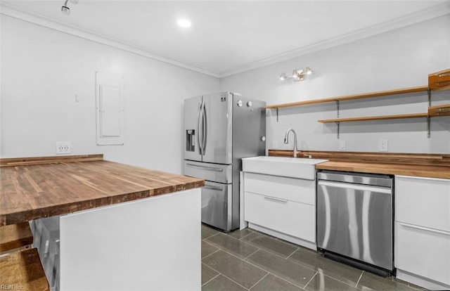 kitchen featuring appliances with stainless steel finishes, crown molding, sink, white cabinets, and butcher block counters