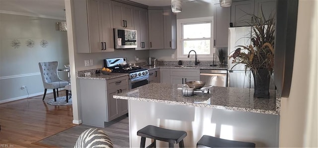 kitchen with kitchen peninsula, appliances with stainless steel finishes, light hardwood / wood-style floors, sink, and gray cabinets