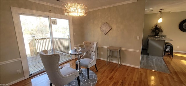 living area with light hardwood / wood-style floors, an inviting chandelier, and ornamental molding