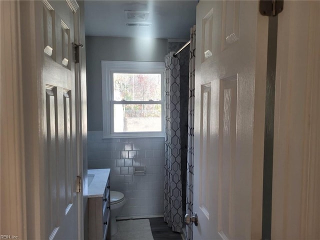 bathroom with vanity, toilet, and tile walls