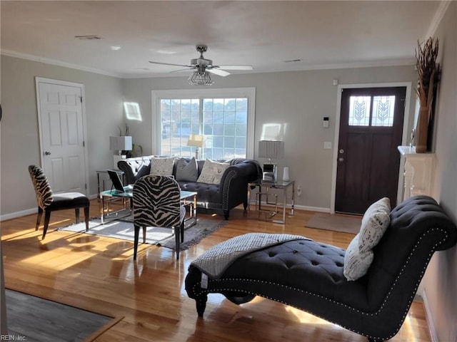 living room featuring ceiling fan, plenty of natural light, crown molding, and light hardwood / wood-style flooring