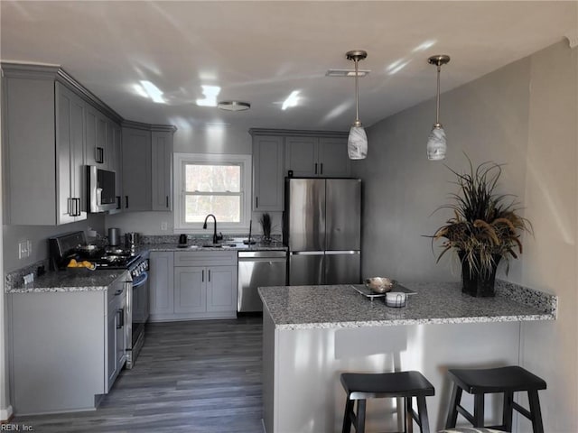 kitchen featuring appliances with stainless steel finishes, light stone counters, hanging light fixtures, and sink