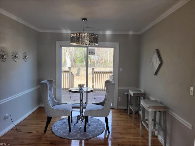 dining space with hardwood / wood-style floors, a notable chandelier, and ornamental molding