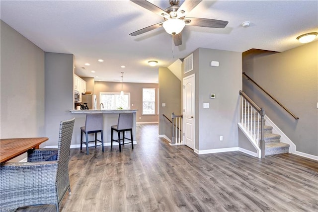 kitchen with kitchen peninsula, appliances with stainless steel finishes, light hardwood / wood-style flooring, white cabinetry, and hanging light fixtures