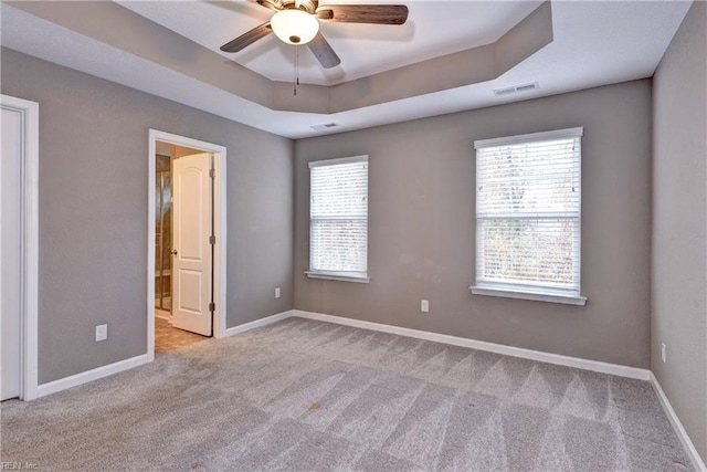 carpeted empty room featuring a raised ceiling and ceiling fan