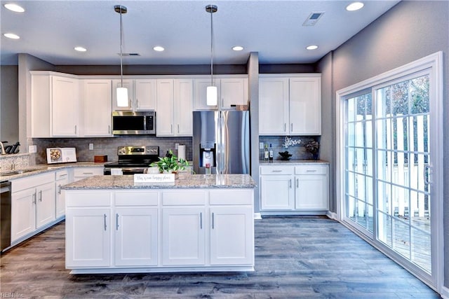 kitchen featuring white cabinetry, wood-type flooring, hanging light fixtures, and appliances with stainless steel finishes