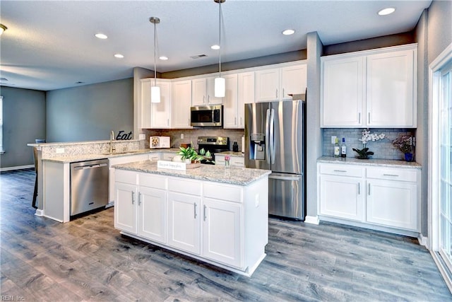 kitchen with white cabinets, decorative light fixtures, stainless steel appliances, and kitchen peninsula