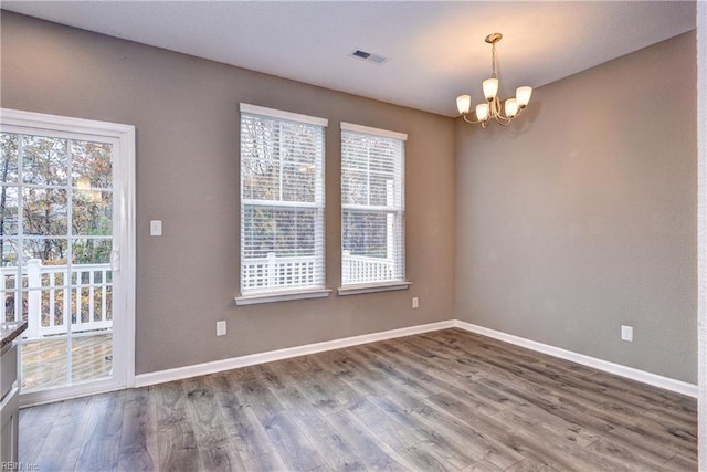 unfurnished dining area with hardwood / wood-style flooring, an inviting chandelier, and a healthy amount of sunlight