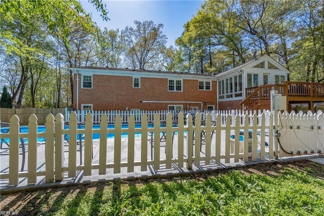 back of property with a pool side deck and a beach view