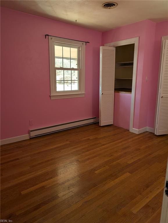 unfurnished bedroom featuring a closet, a baseboard radiator, and dark hardwood / wood-style floors