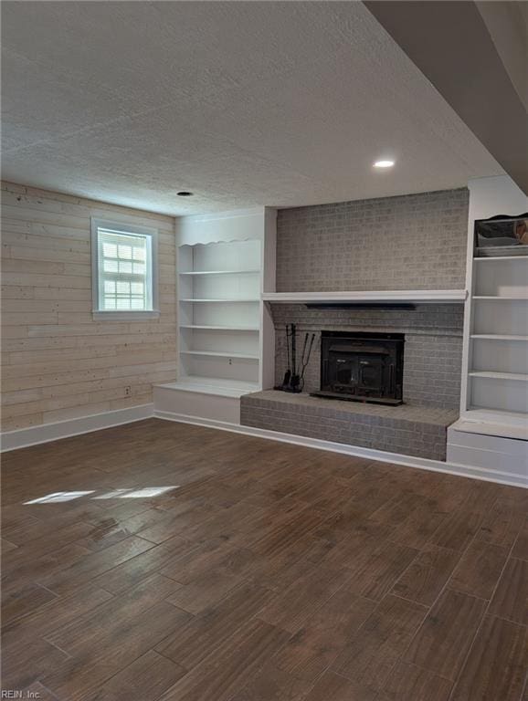 unfurnished living room featuring dark wood-type flooring, a fireplace, and a textured ceiling