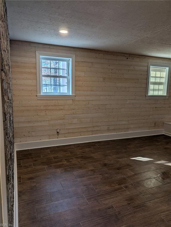 empty room with wooden walls, dark hardwood / wood-style floors, and a textured ceiling