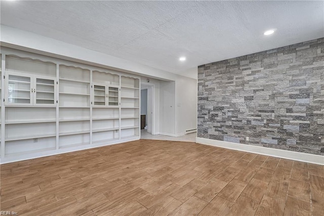 basement with hardwood / wood-style flooring, a baseboard heating unit, and a textured ceiling