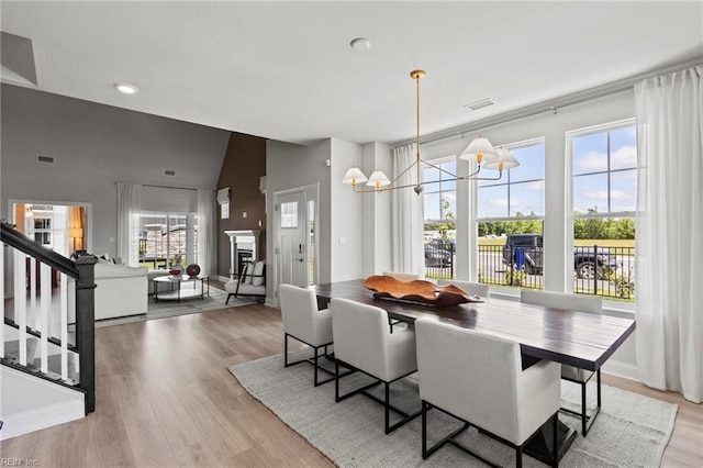 dining space with light hardwood / wood-style floors, high vaulted ceiling, and an inviting chandelier