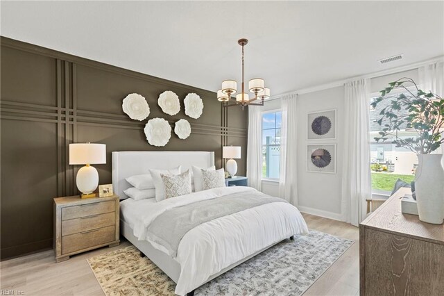 bedroom with ornamental molding, light wood-type flooring, and a notable chandelier