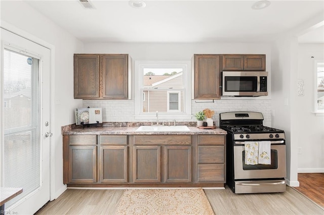 kitchen featuring sink, light wood-type flooring, stainless steel appliances, and a wealth of natural light