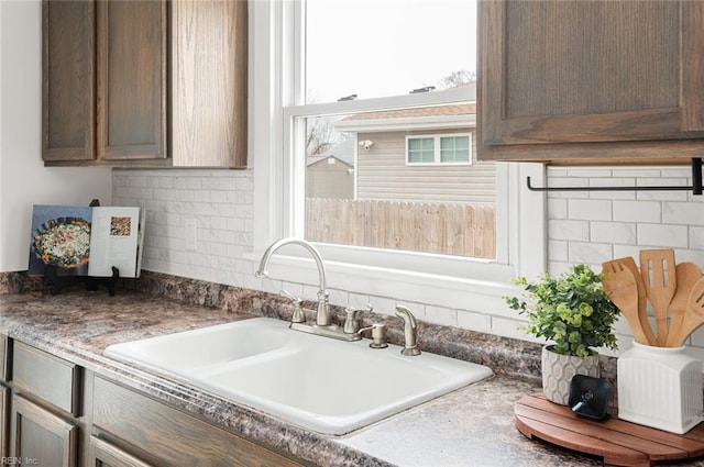 kitchen with dark brown cabinetry, tasteful backsplash, and sink