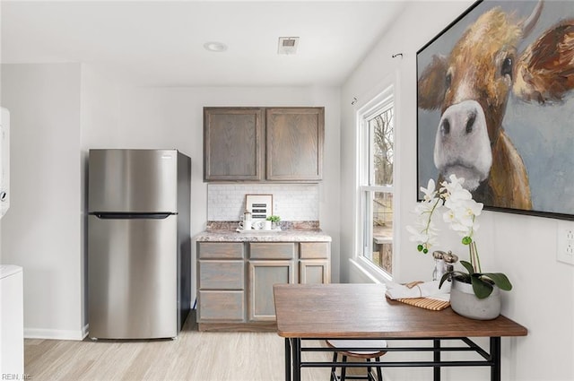 kitchen with decorative backsplash, stainless steel fridge, and light wood-type flooring