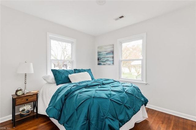 bedroom with multiple windows and dark hardwood / wood-style flooring