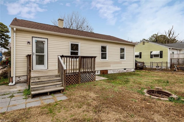 rear view of property with a fire pit, a deck, and a lawn