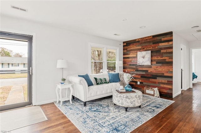 living room featuring a healthy amount of sunlight, wood-type flooring, and wooden walls