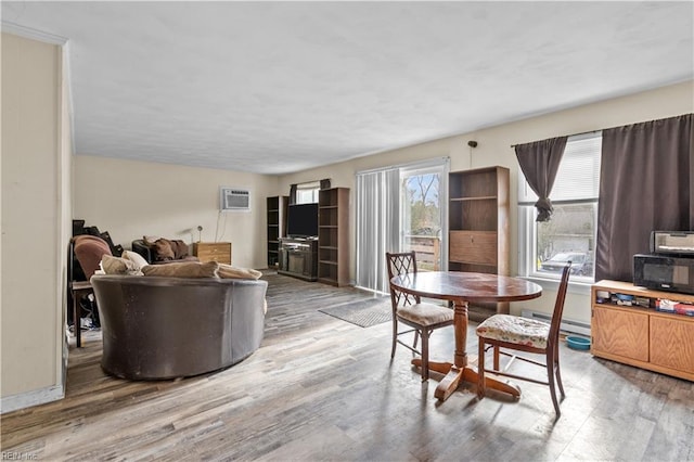 dining room with an AC wall unit, light hardwood / wood-style flooring, and a baseboard heating unit