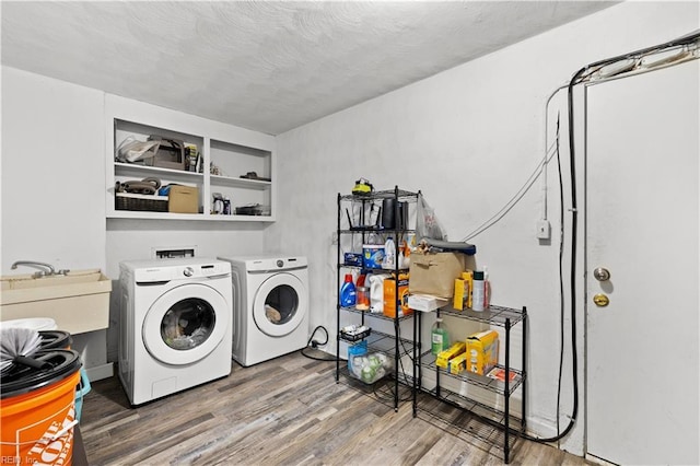 clothes washing area with hardwood / wood-style floors, a textured ceiling, sink, and washing machine and clothes dryer